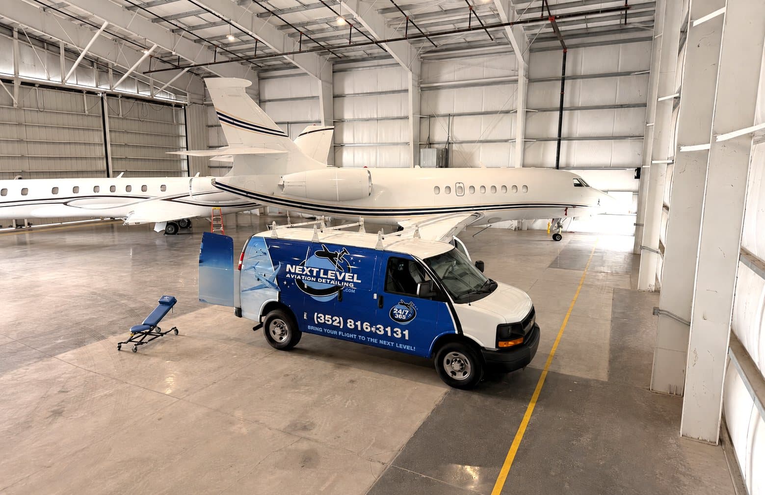 Next Level van parked beside a private jet in the hangar